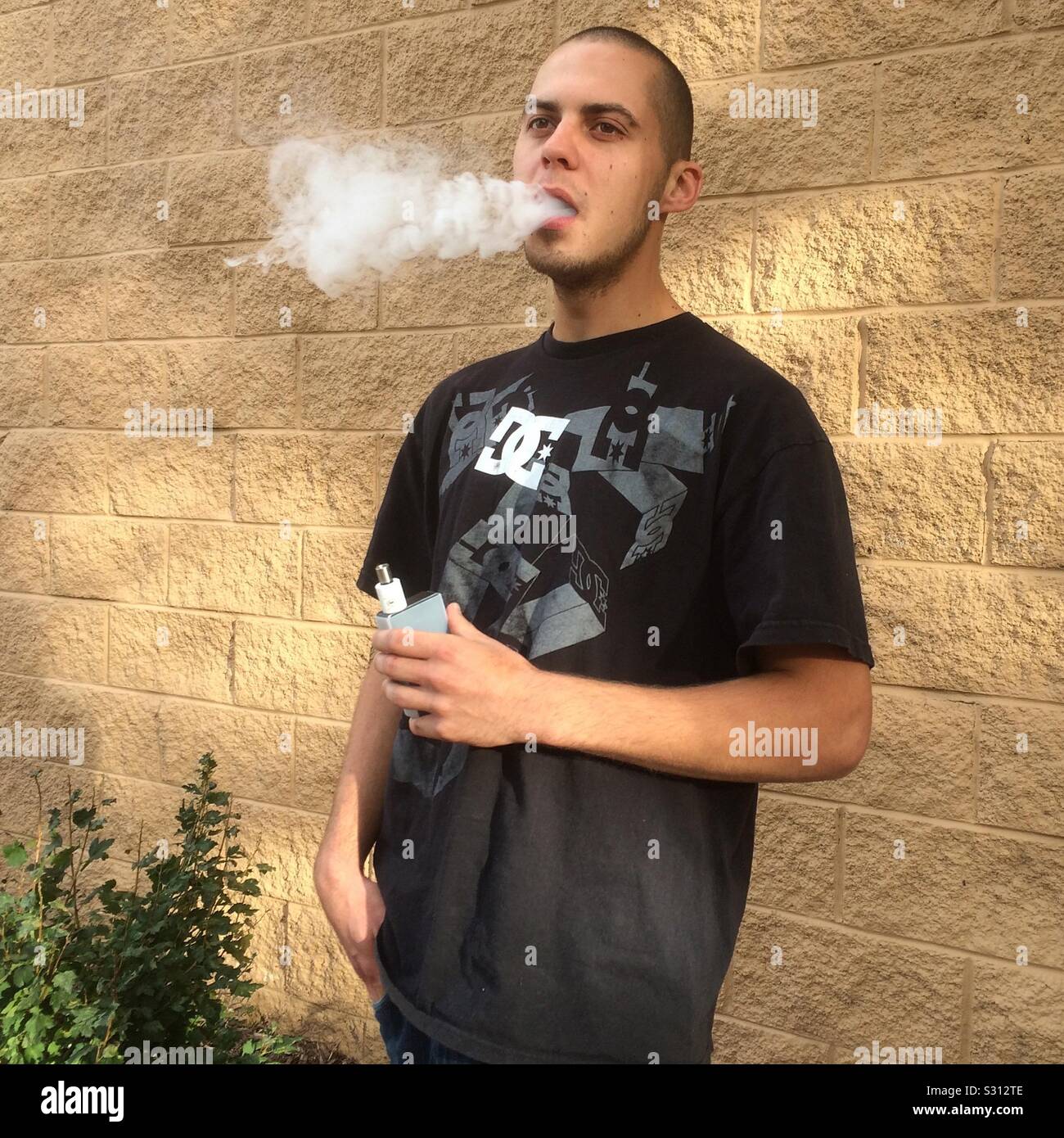 A young man exhales vape smoke. Stock Photo