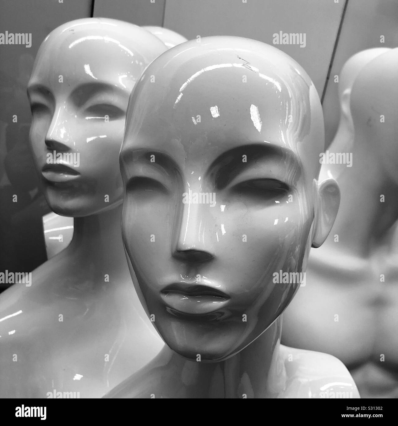A black and white closeup of bald female mannequin heads Stock Photo