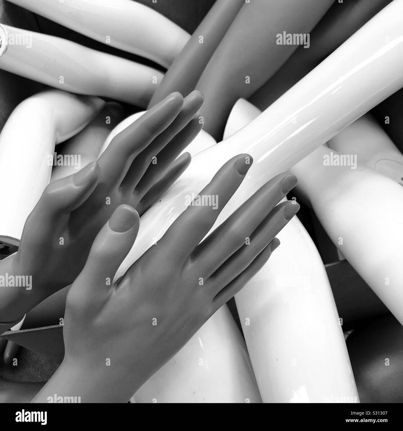 The hands of a mannequin amidst a pile of mannequin arms and hands in black and white Stock Photo
