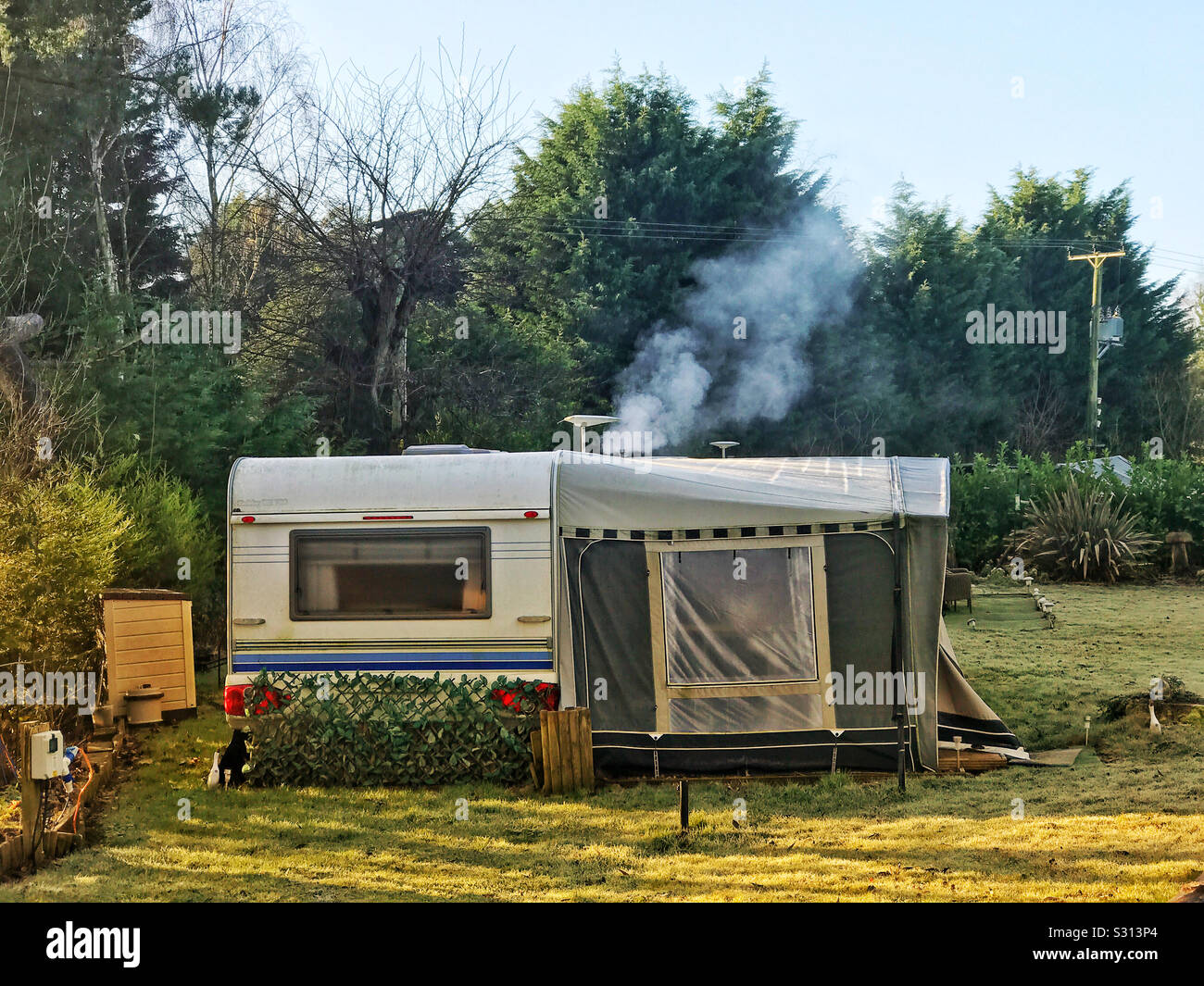 Large touring caravan with awning and heating on, in winter. Stock Photo