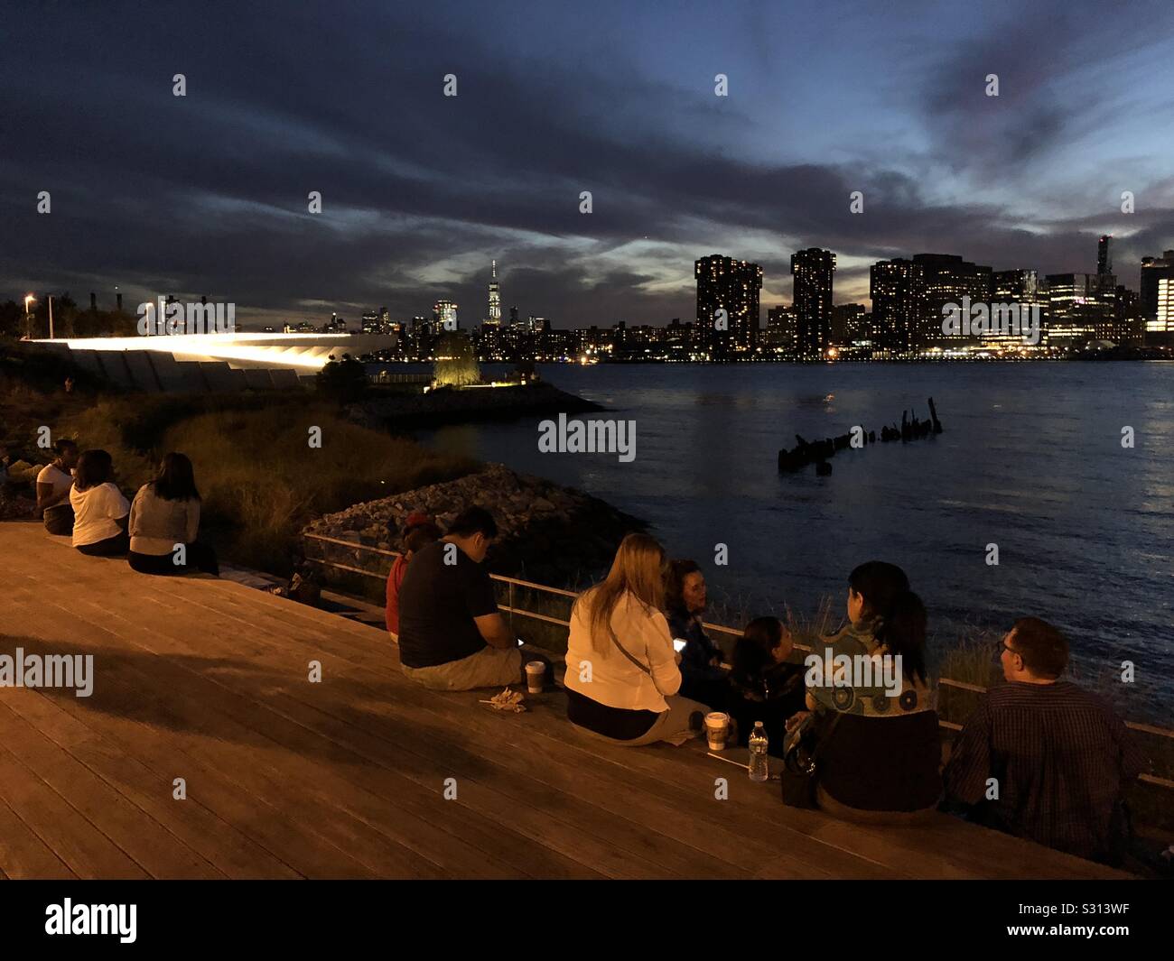 Group of people mingling in a Summer Evening at the Gantry State Park in Long Island City - Smartphone Captured Stock Image