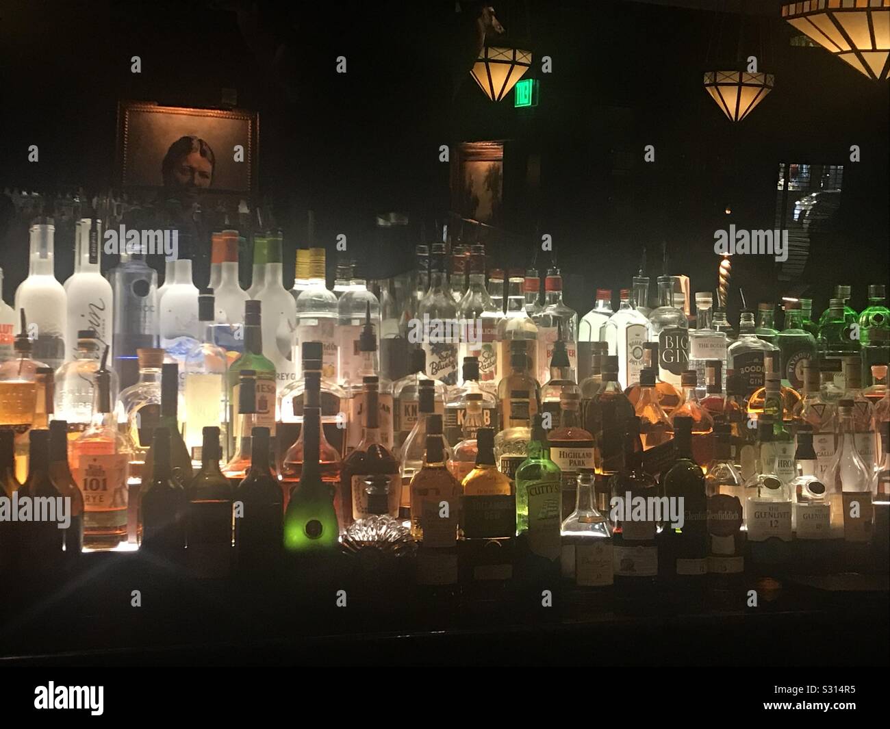 Backlit bar and assortment of liquors displayed - Smartphone Captured Stock Image