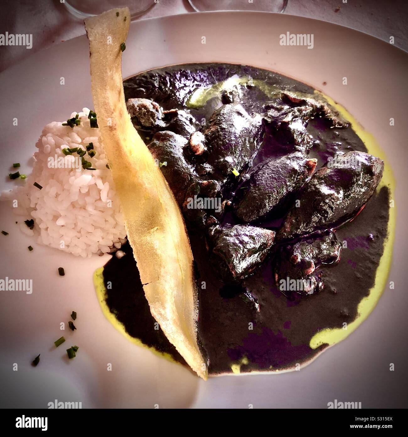 Chipirones en su tinta (calamari in ink sauce) in restaurant aita mari, San Sebastián, Basque Country - Smartphone Captured Stock Image