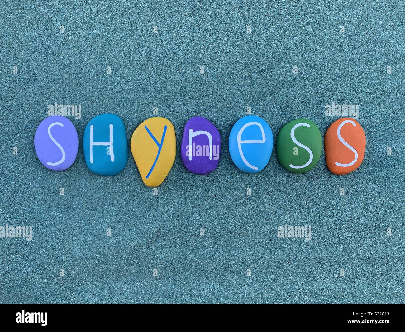 Shyness word composed with multi colored stone letters over green sand Stock Photo
