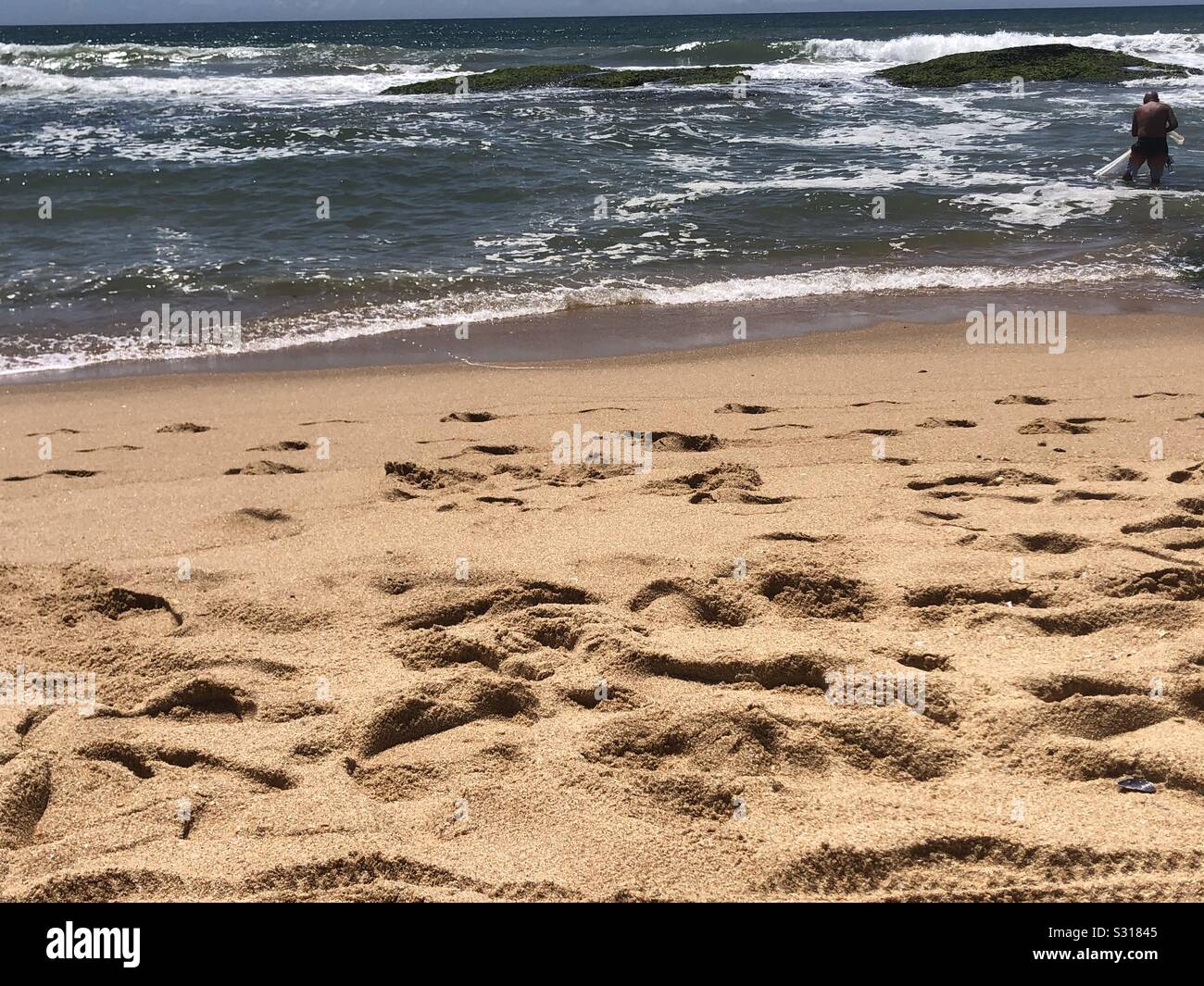 Lone Fisherman plies his Trade by a well travelled beach - Smartphone Captured Stock Image