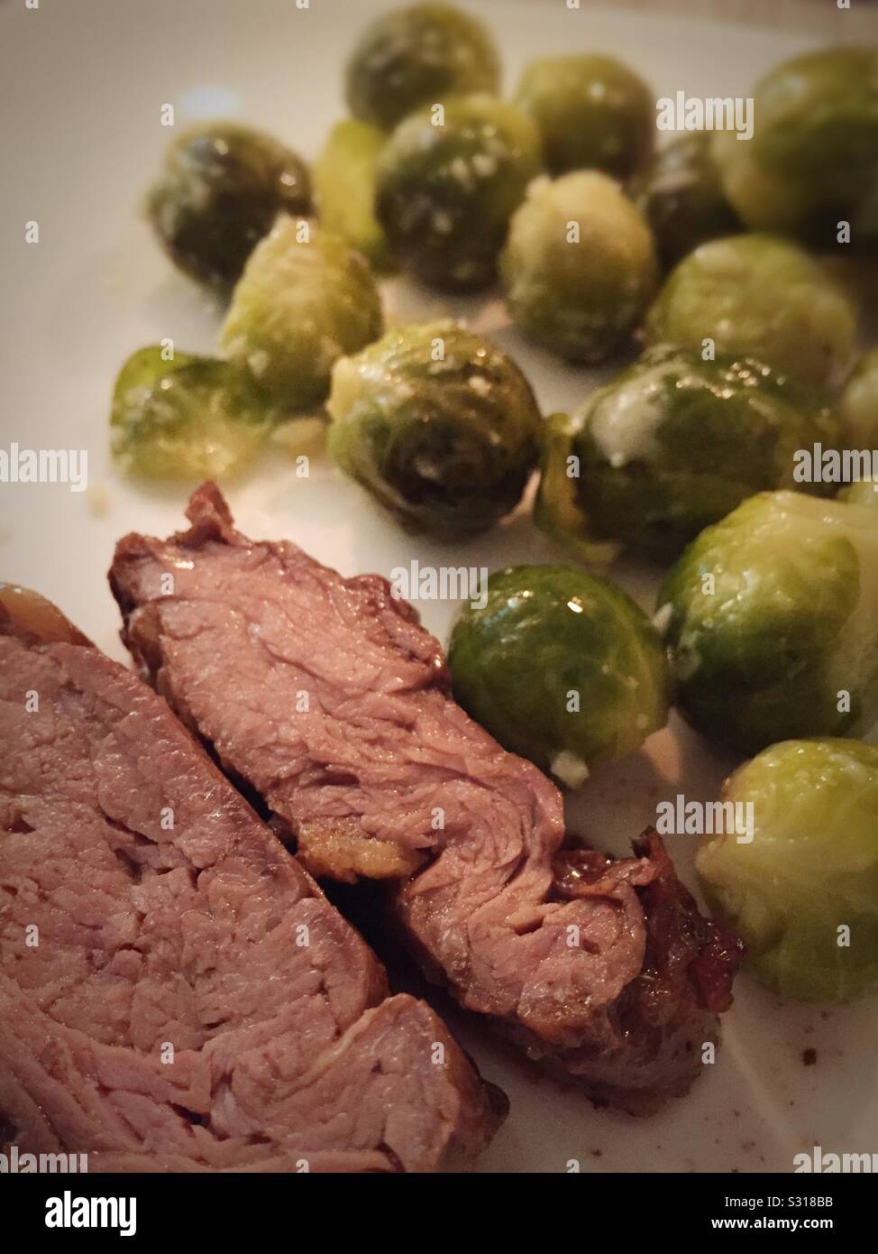 Close up of a hearty home-cooked meal of medium rare beef tenderloin and steamed Brussels sprouts - Smartphone Captured Stock Image