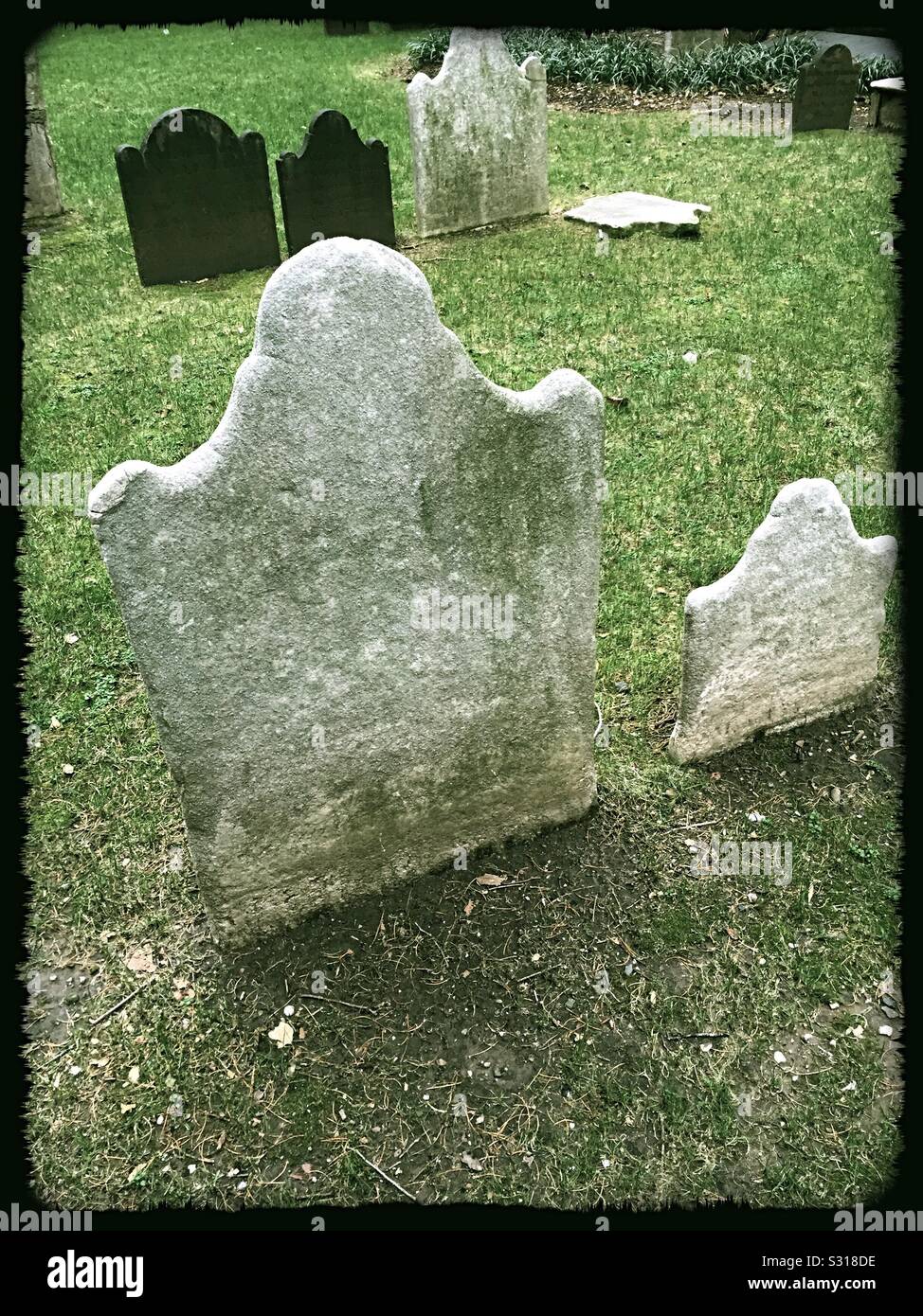 Historic ancient tombstones worn smooth over the ages in a cemetery, USA - Smartphone Captured Stock Image