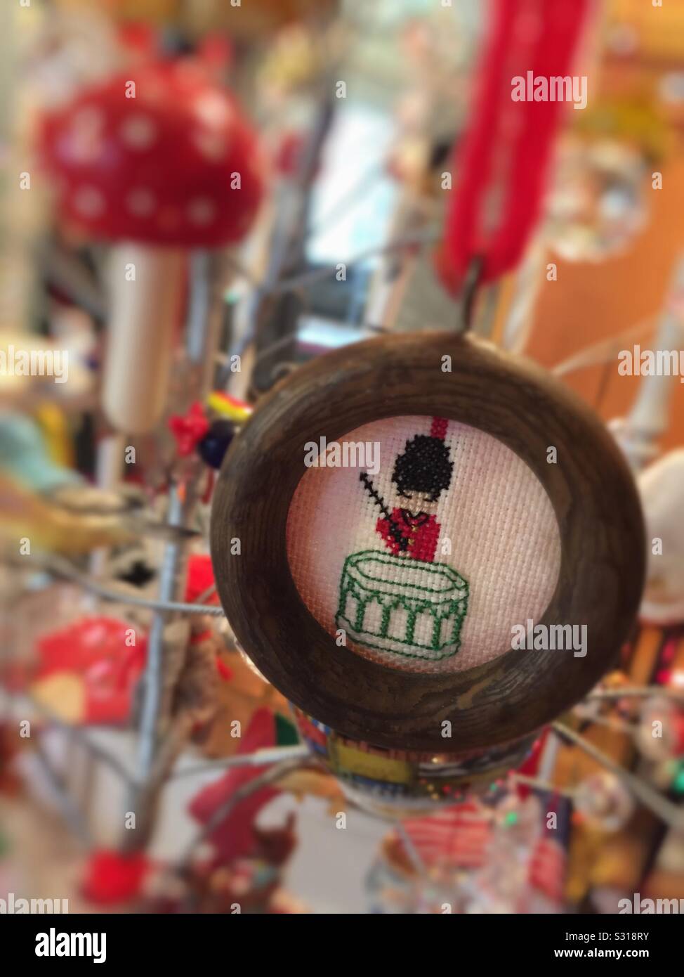 A homemade Crosstitch ornament of a soldier and his drum hangs from a Christmas tree in the holiday season - Smartphone Captured Stock Image