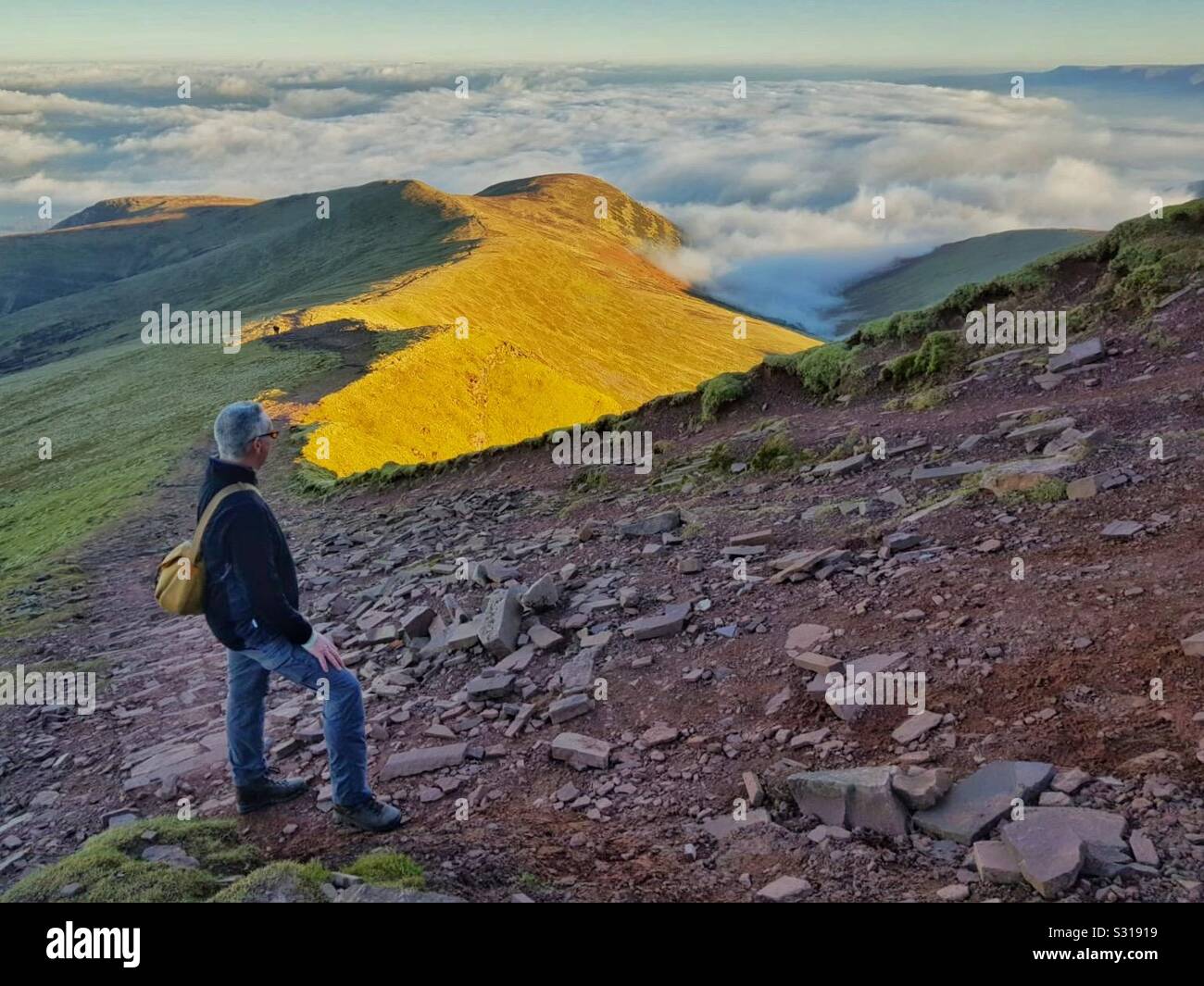 Man looking down Cefn Cwm Llwch on the approach to the summit of Pen y Fan, Brecon Beacons, Wales, December. - Smartphone Captured Stock Image