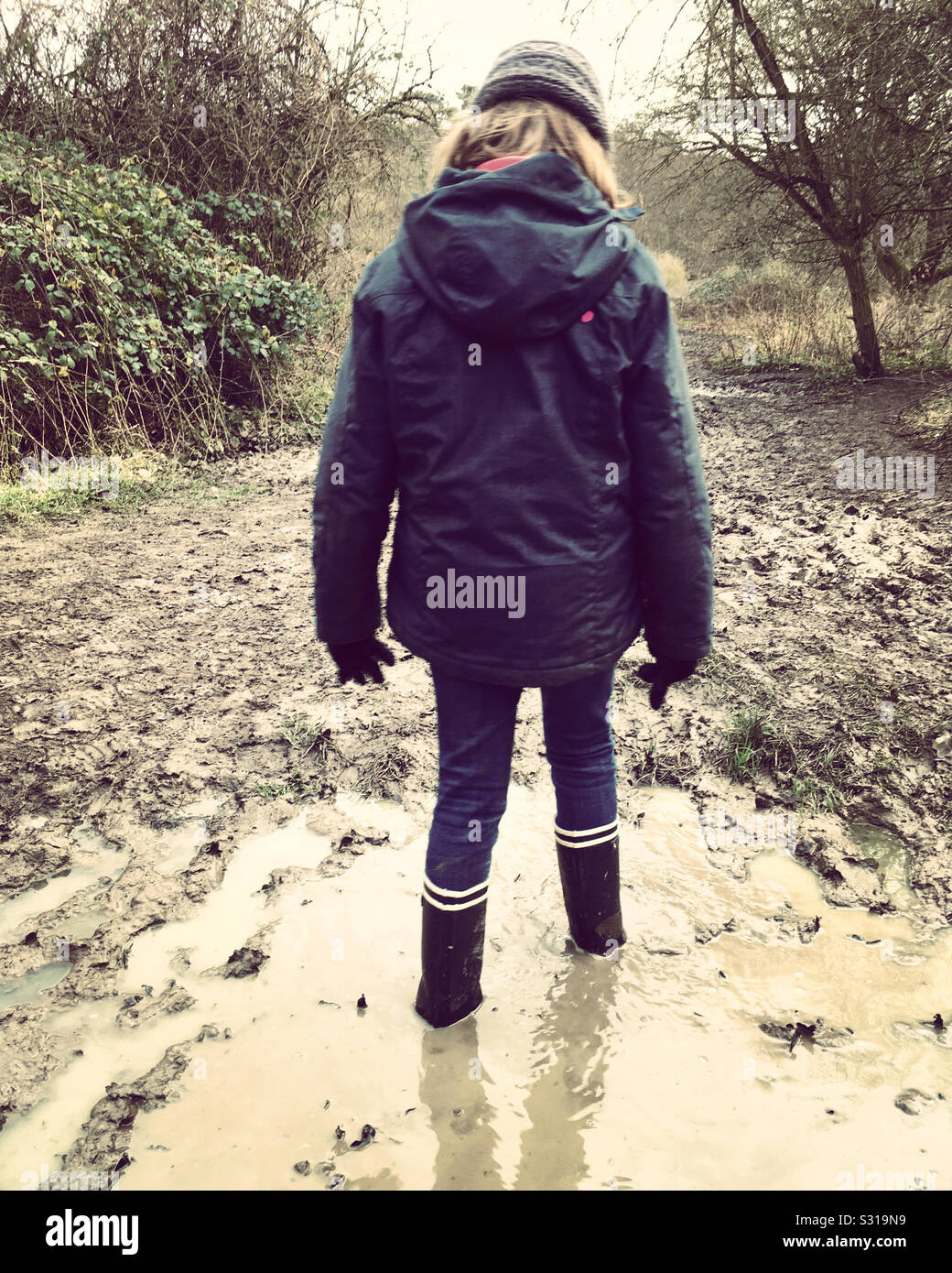 Thoughtful child in water and mud. Girl aged age 7 years stuck in a muddy  puddle well wearing Wellington boots Stock Photo - Alamy