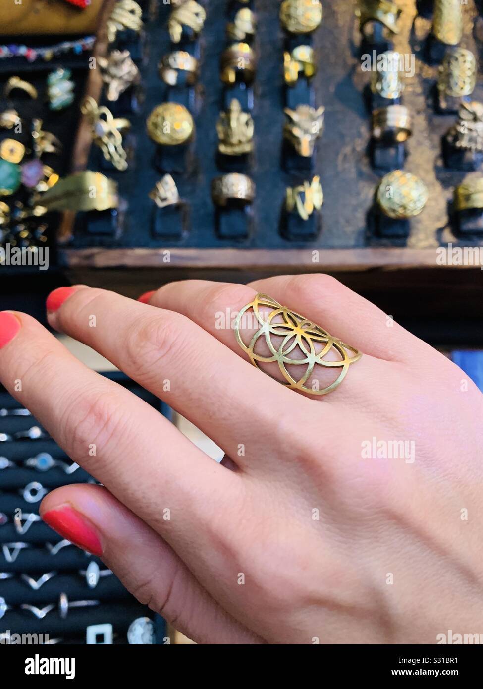 Trying on a seed of life ring at a jewellery stall with ring display in the background Stock Photo