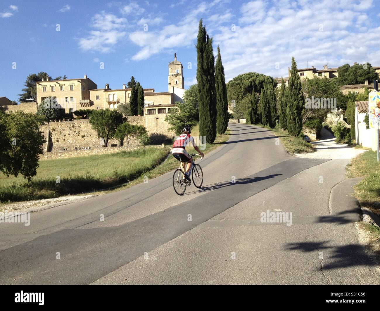 A young man riding a bicycle by the town of Maubec, France wearing a helmet and riding clothes. - Smartphone Captured Stock Image