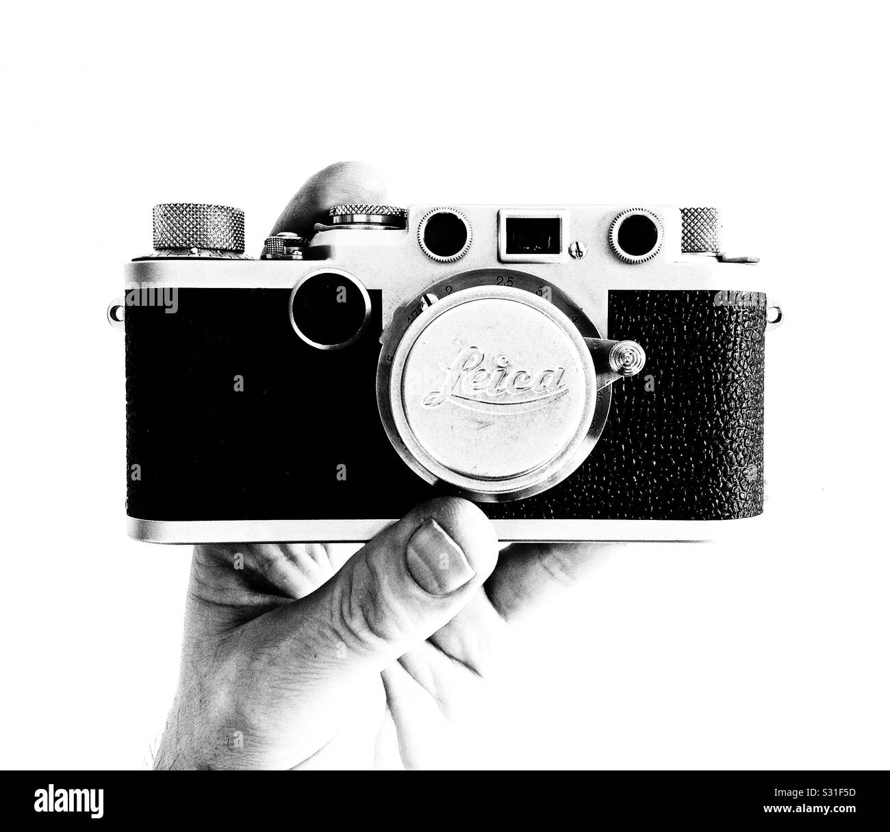 A high-contrast black-and-white photograph of a man’s hand holding a Leica IIf with a 35 mm f/3.5 Elmar lens - Smartphone Captured Stock Image