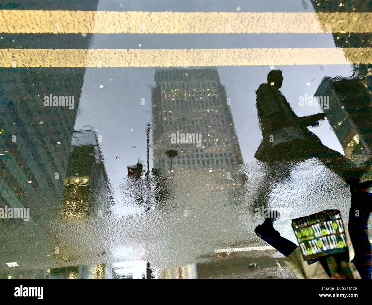 Silhouette of man reflection in puddle on a rainy day in Canary Wharf - Smartphone Captured Stock Image