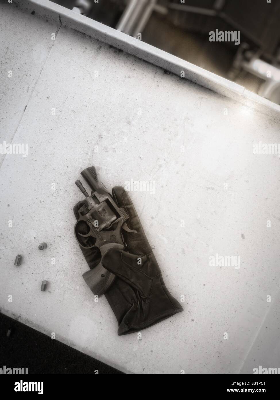 Leather glove pistol and bullets on ledge high above city street, depicting crime, escape from a crime, criminals, contract killing Stock Photo