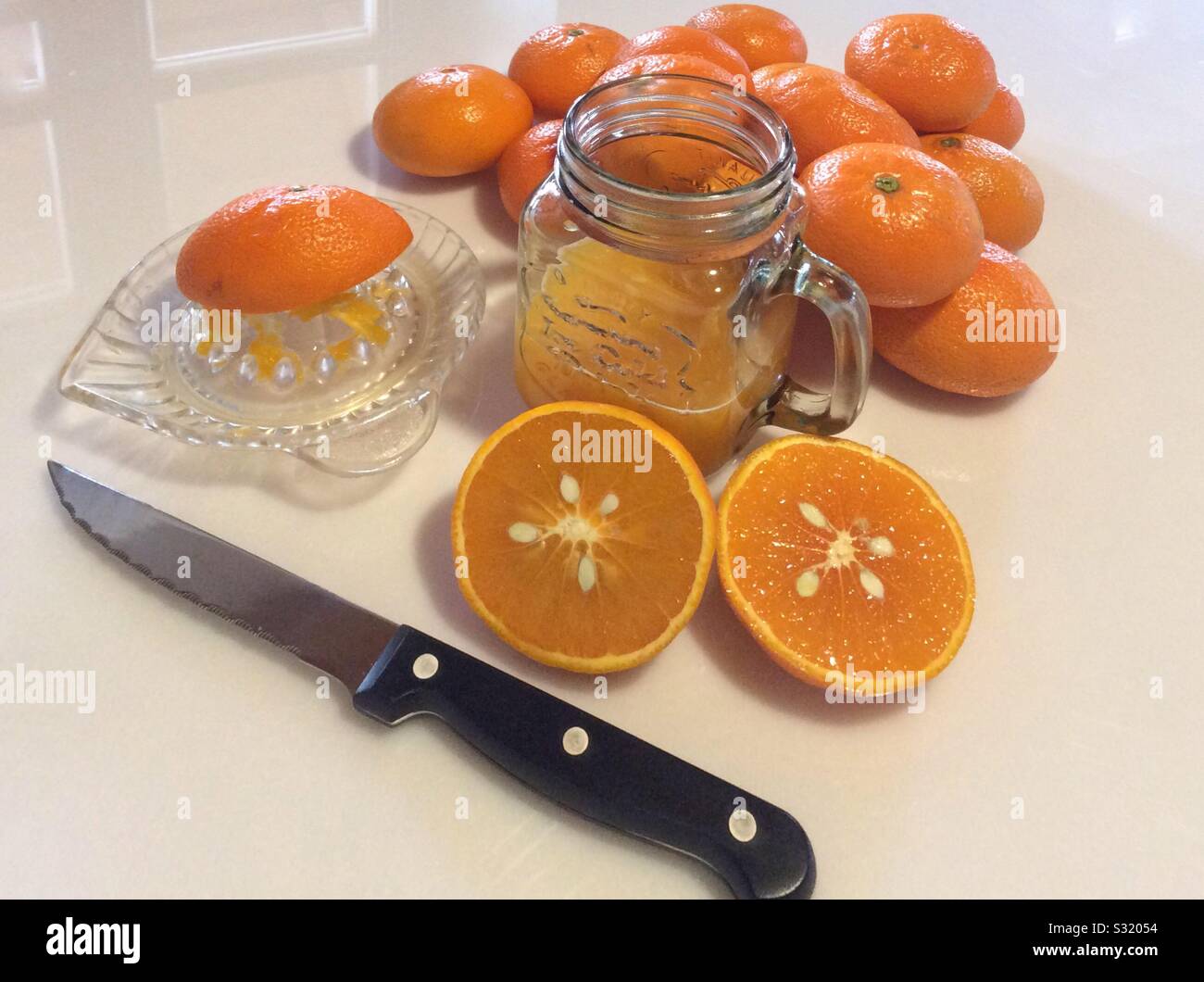 refreshing vitamine C drink with tangerine juice in glass, Knife and citrus glass juicer on a white background Stock Photo