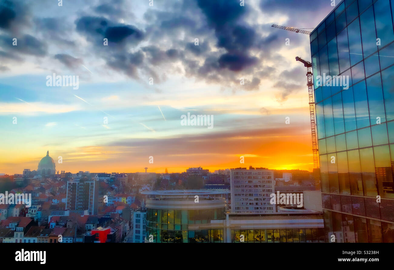 Colorful sunrise and dark dramatic clouds over the business district of the city and reflected in the windows of the office buildings Stock Photo