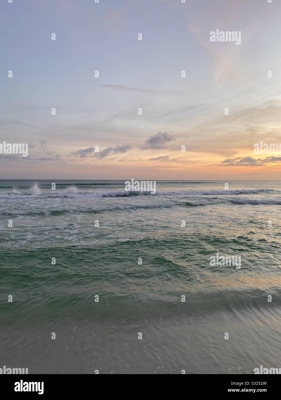 Evening sunset skies on the beach with soft colorful colors and waves on the water - Smartphone Captured Stock Image