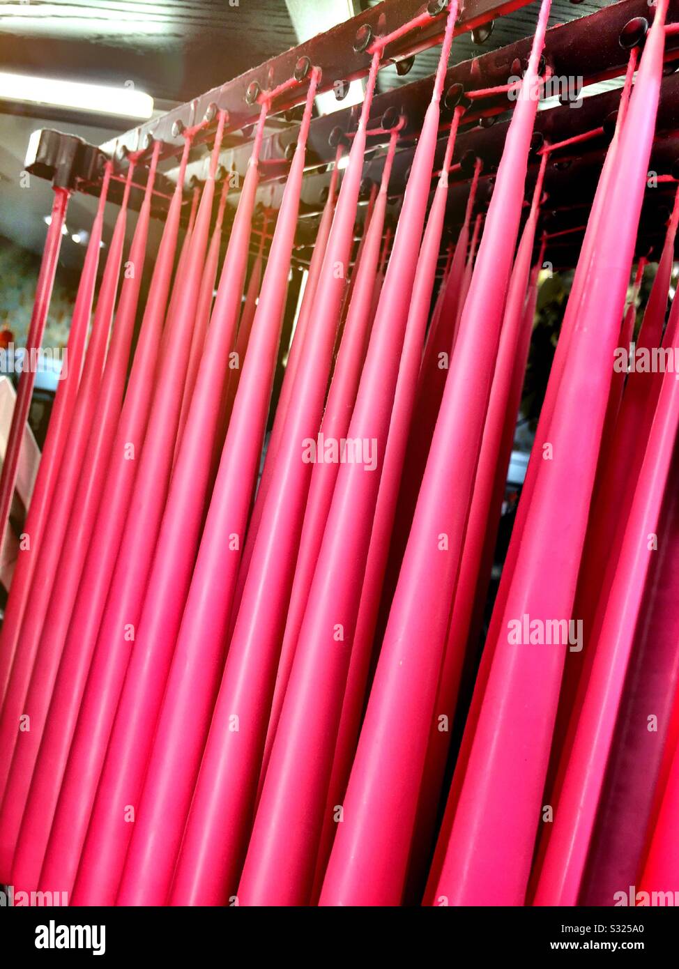 Pink taper candles hanging in a display rack for sale at a retail shop in New York City, USA - Smartphone Captured Stock Image
