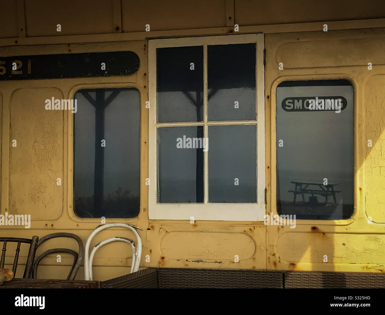 Old railway carriage beach house. With reflections of sea and smoking sign. - Smartphone Captured Stock Image