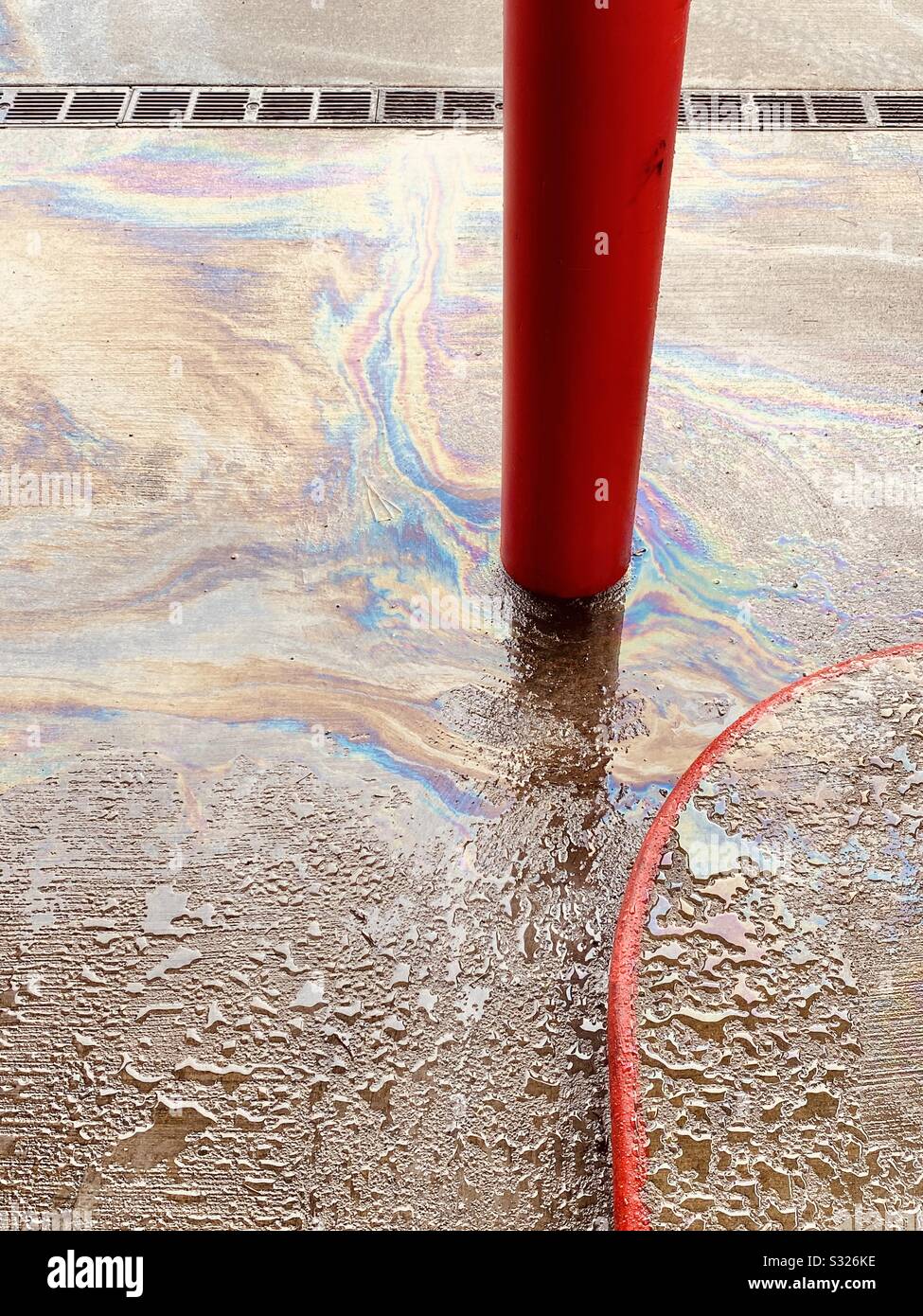 Petrol, or gasoline spilled on the ground at a gas station in the rain - Smartphone Captured Stock Image