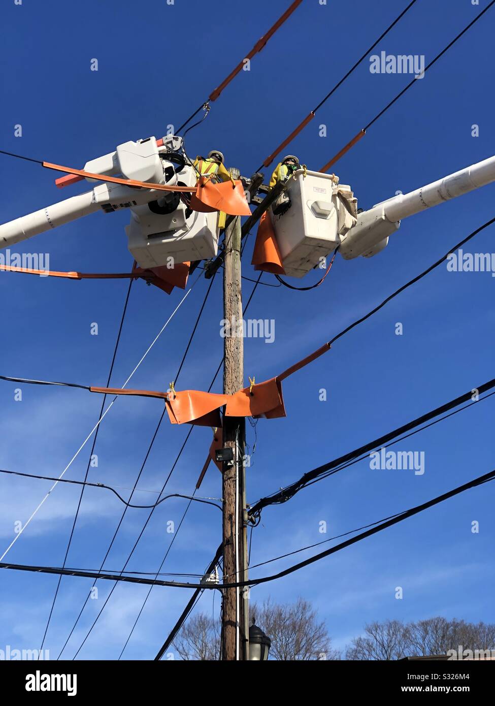 Utility workers in truck buckets working on electrical wires. Stock Photo