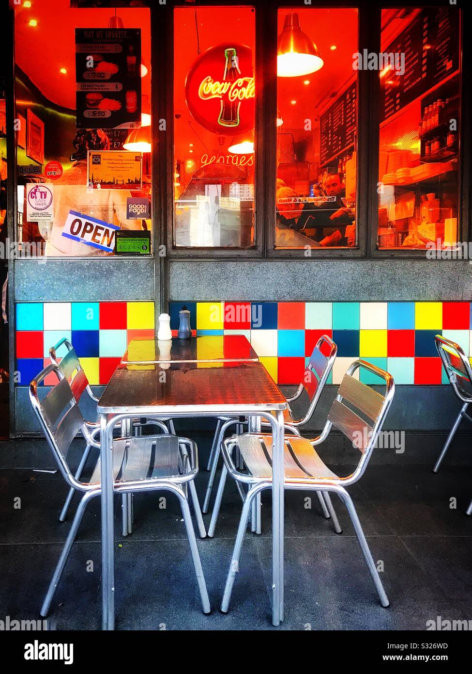 Aluminium table and chairs outside a cafe in Portobello Road , London. Colourful ceramic tiles which are on the wall under the front window, attract the attention of the passerby Stock Photo
