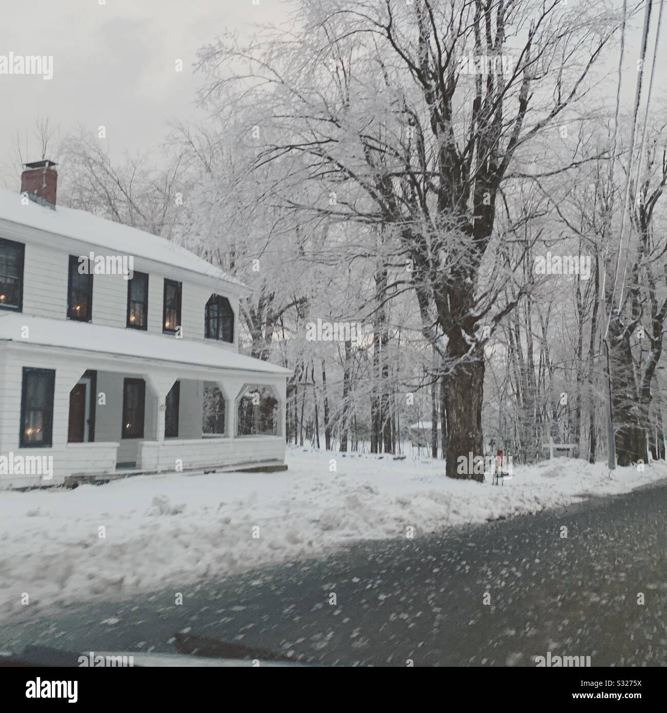 Driving by a home on a rural road in winter, New England, United States - Smartphone Captured Stock Image