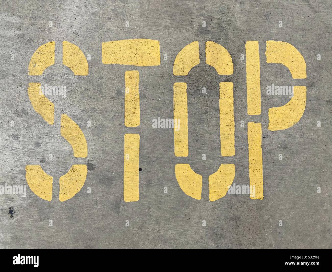 Stop sign letter stencil with yellow paint on concrete Stock Photo