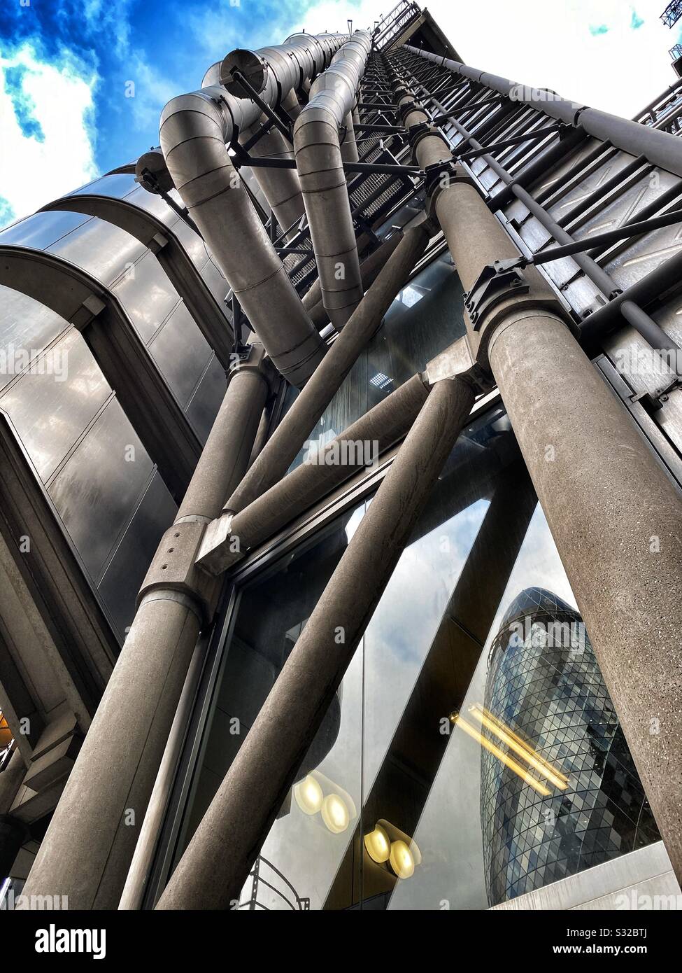 The Gherkin skyscraper is reflected in the Lloyd’s of London building, in London, UK in January 2020 - Smartphone Captured Stock Image