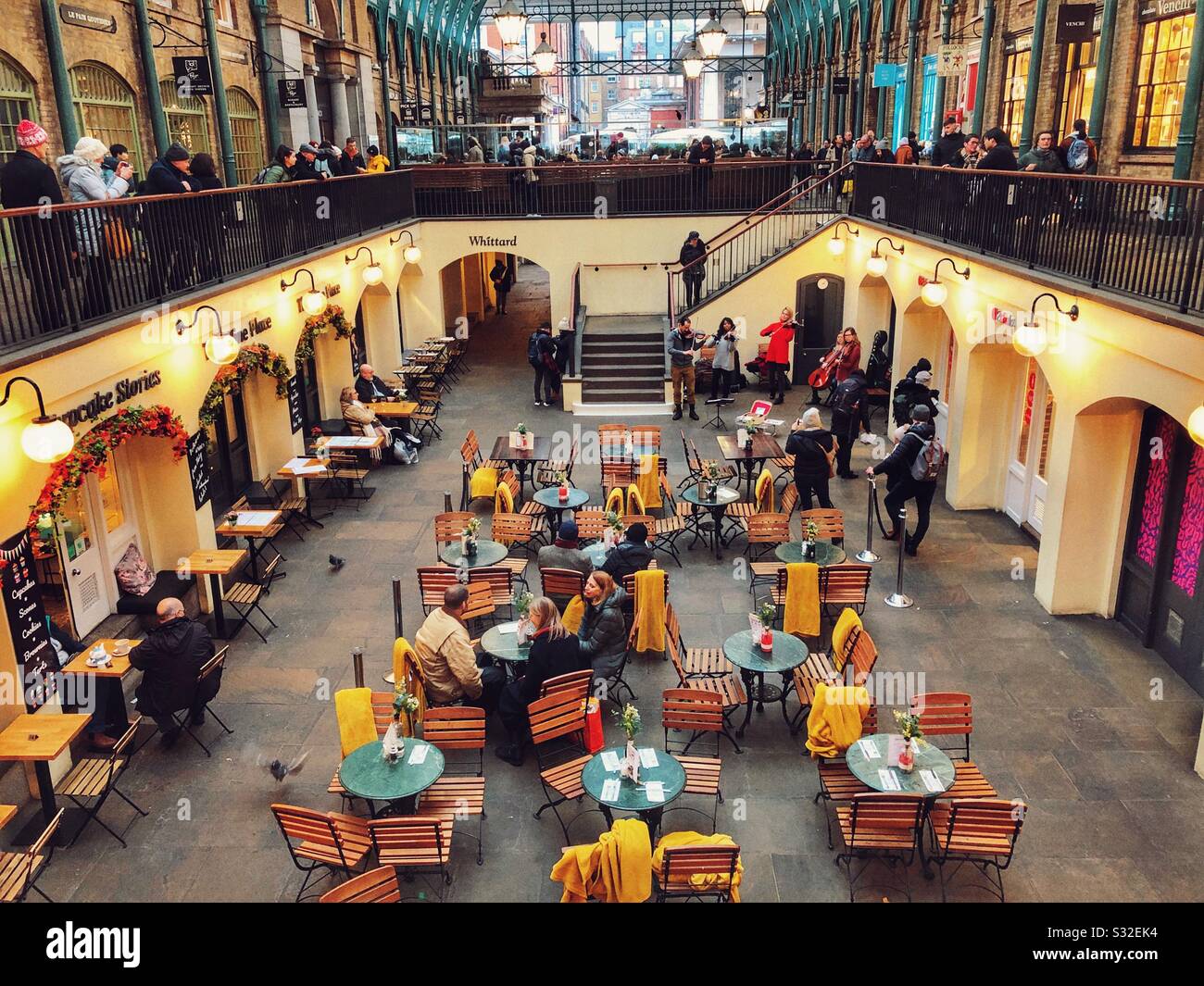 Buskers with people at the cafe tables and on the walkways of The South Hall, Covent Garden, London, England Stock Photo