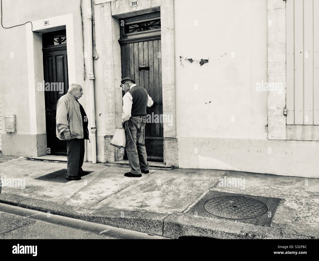 Two older Frenchmen conversing on the street in Provence, France. Stock Photo