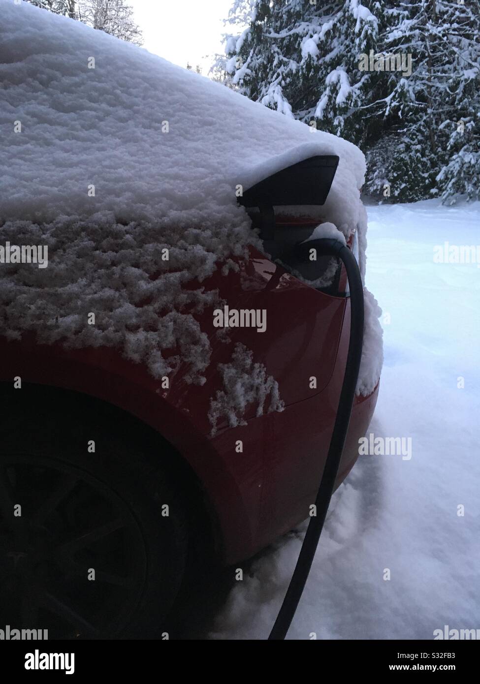 Electric car in snow plugged in Stock Photo Alamy