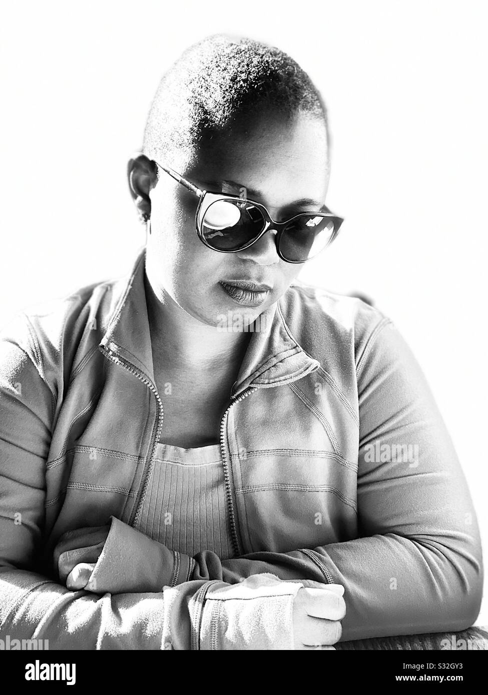 A young African-American woman wearing sunglasses sis deep in thought. - Smartphone Captured Stock Image