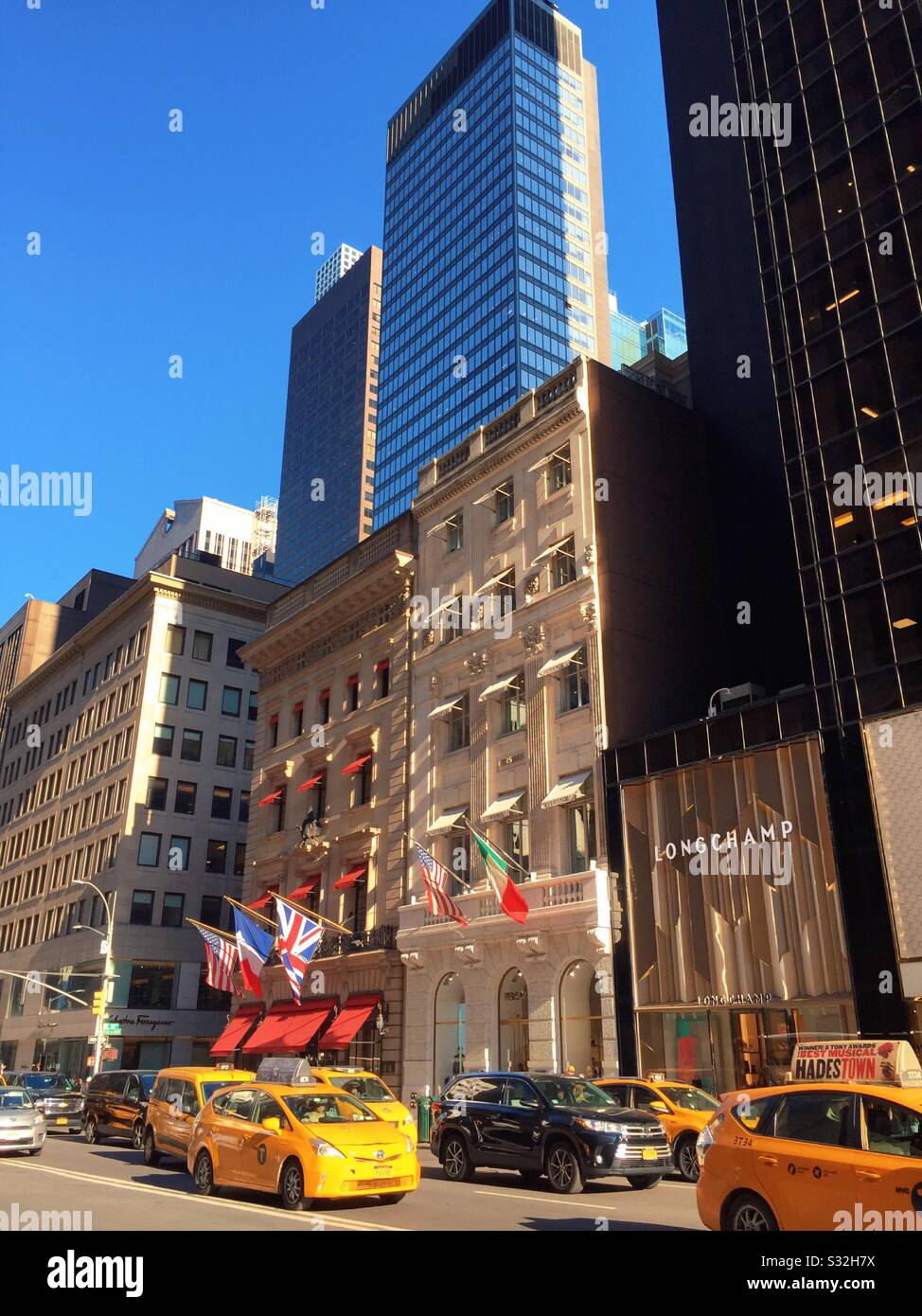Yellow taxis move along fifth Avenue in front of World famous high end stores, New York City, United States - Smartphone Captured Stock Image