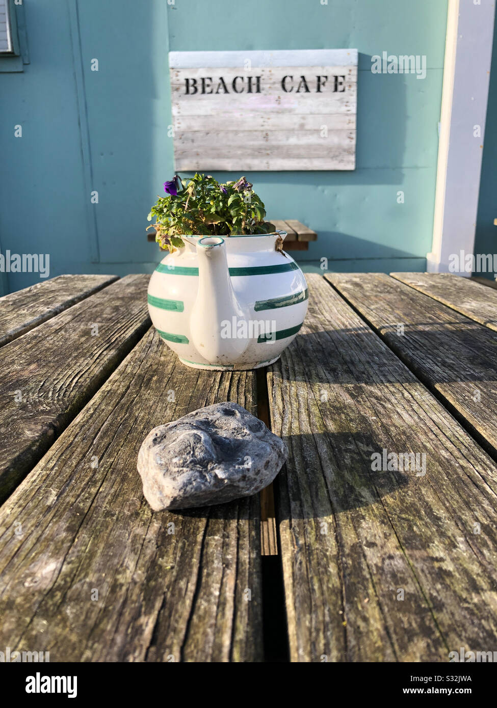 Outdoor table at a beachside café with teapot planter Stock Photo