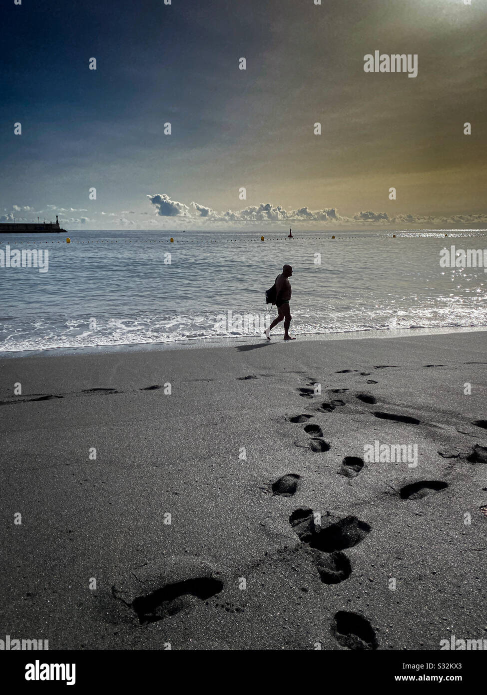 Hombre paseando disfrutando de una mañana de relax en la playa Stock Photo