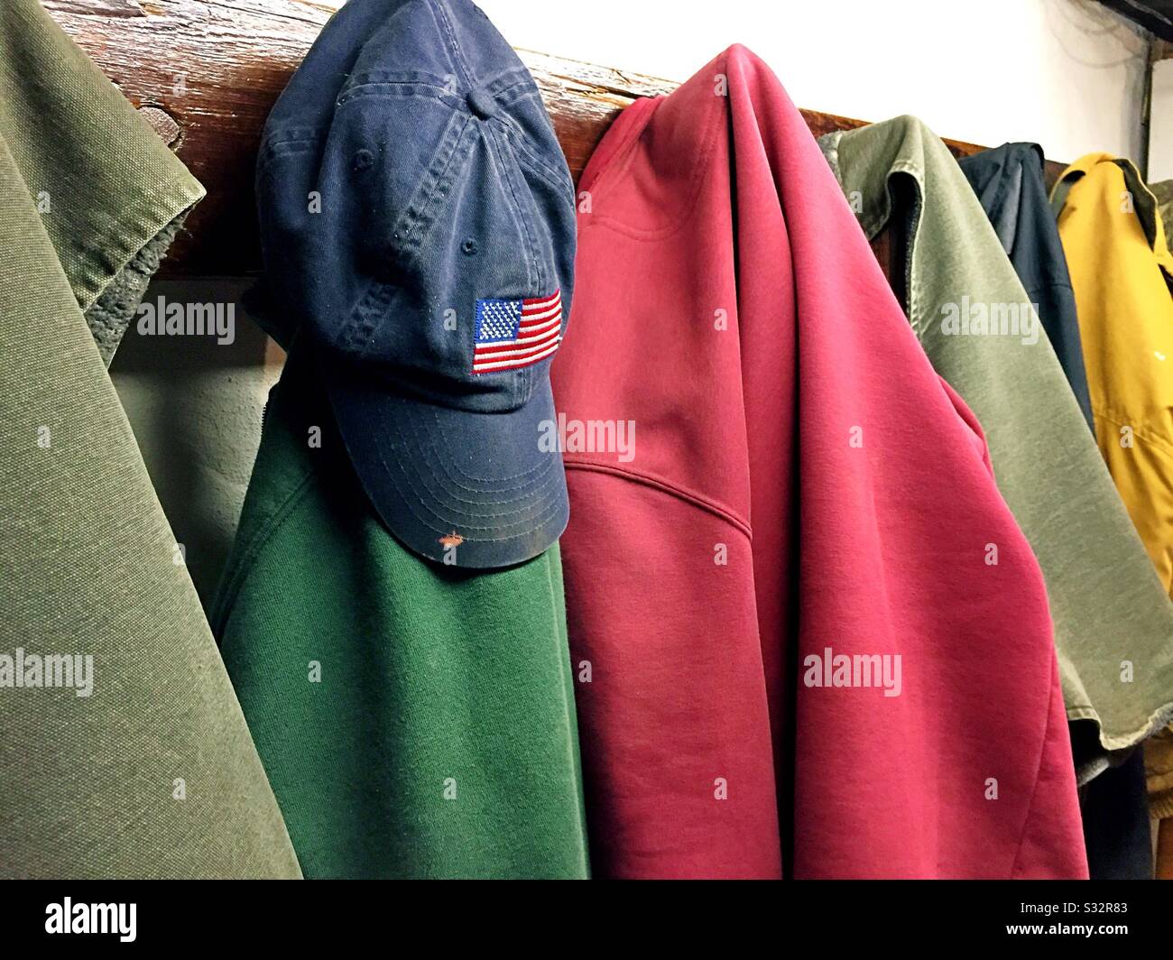 Work clothes and ball cap hanging from a coat rack, United States - Smartphone Captured Stock Image