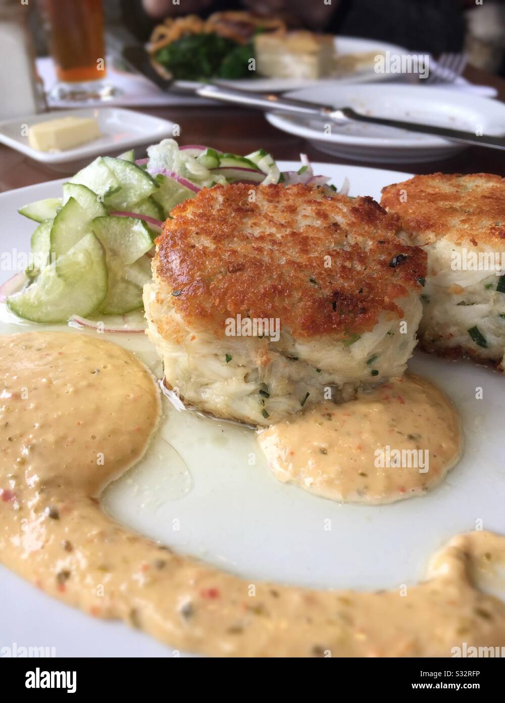 Gourmet entrée of jumbo lump crab cakes with a cucumber salad and red