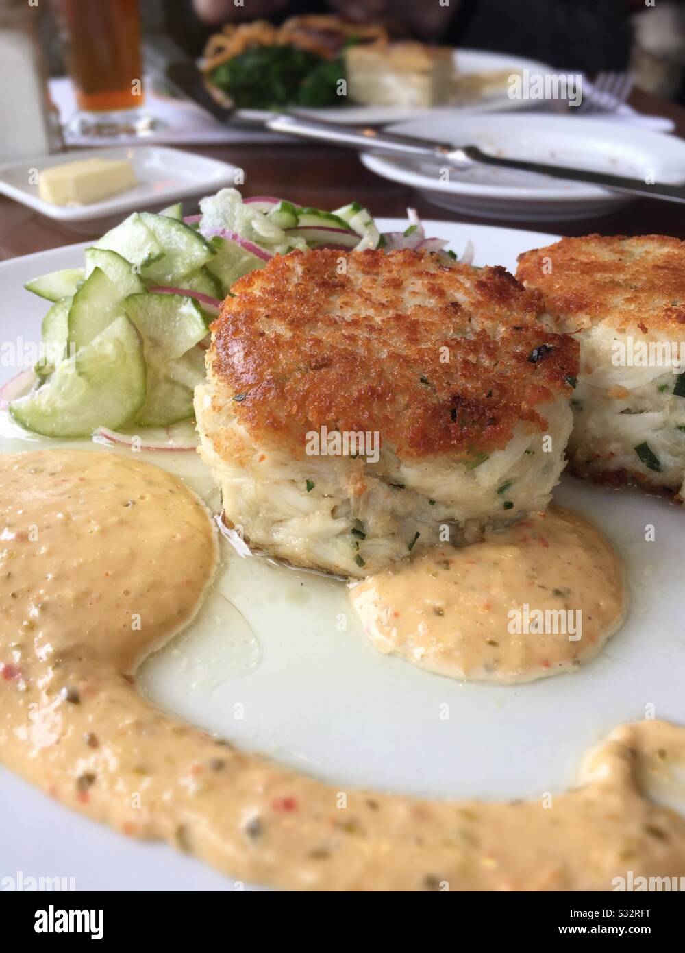 Gourmet entrée of jumbo lump crab cakes with a cucumber salad and a red bell pepper remoulade USA - Smartphone Captured Stock Image