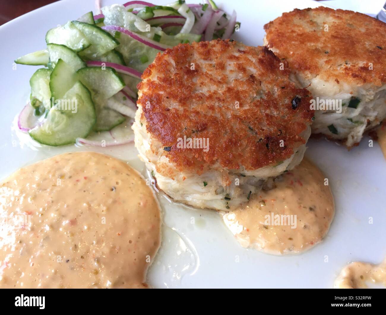 Gourmet entrée of jumbo lump crab cakes with a cucumber salad and a red