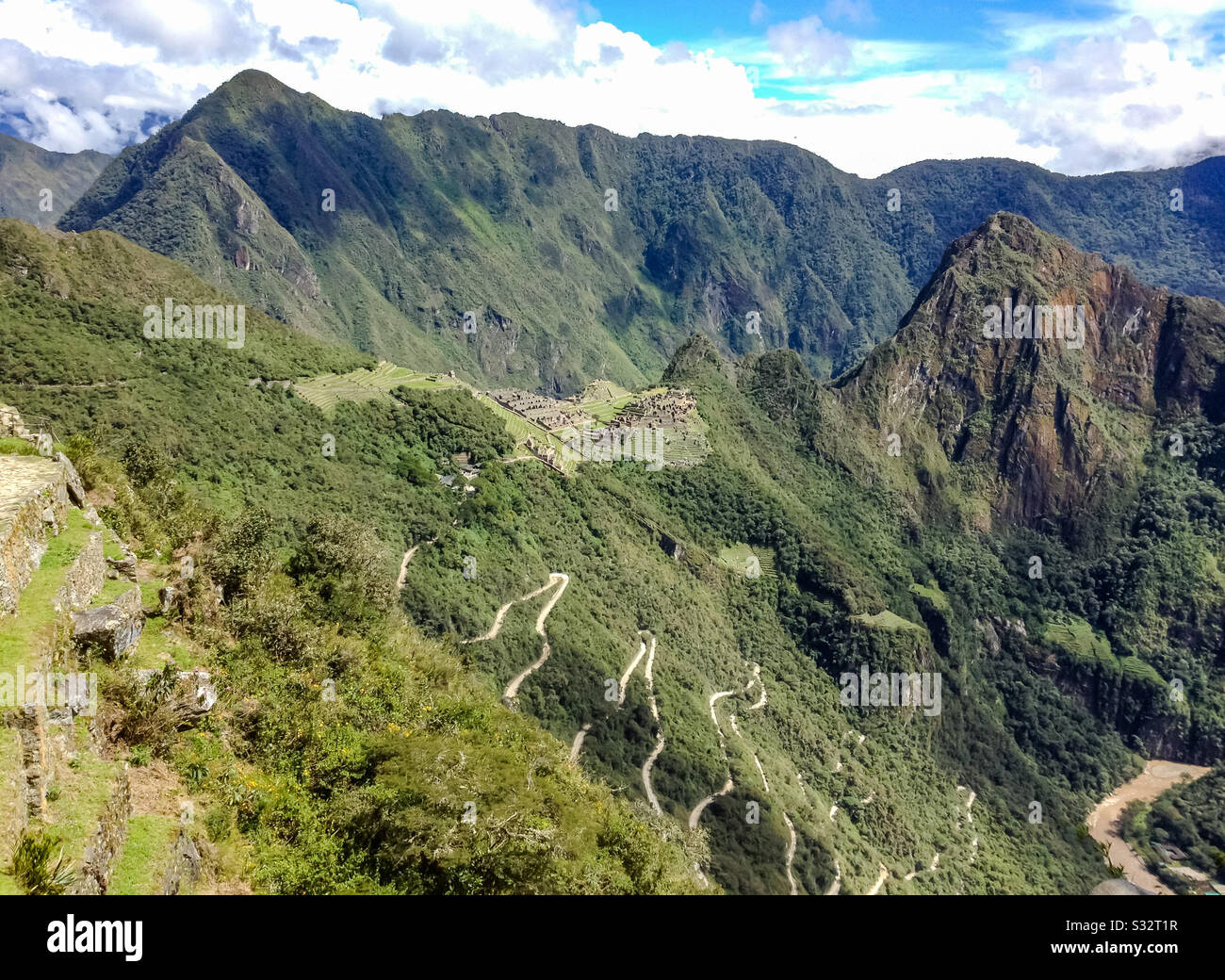 View of zigzag switchback road leading up to Machu Picchu archaeological site with mountain backdrop, Peru, South America - Smartphone Captured Stock Image