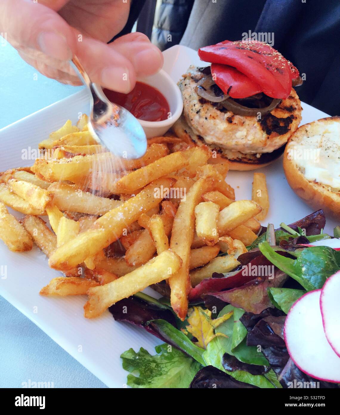 Male diner salting french fries while dining at a fine restaurant, USA - Smartphone Captured Stock Image