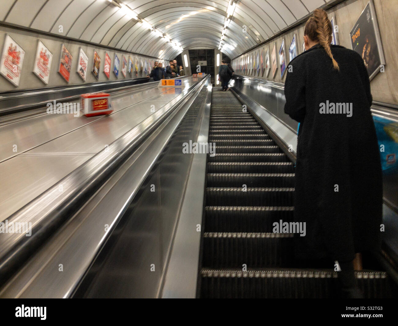 A lady travelling up on an escalator in a London Underground Station. - Smartphone Captured Stock Image