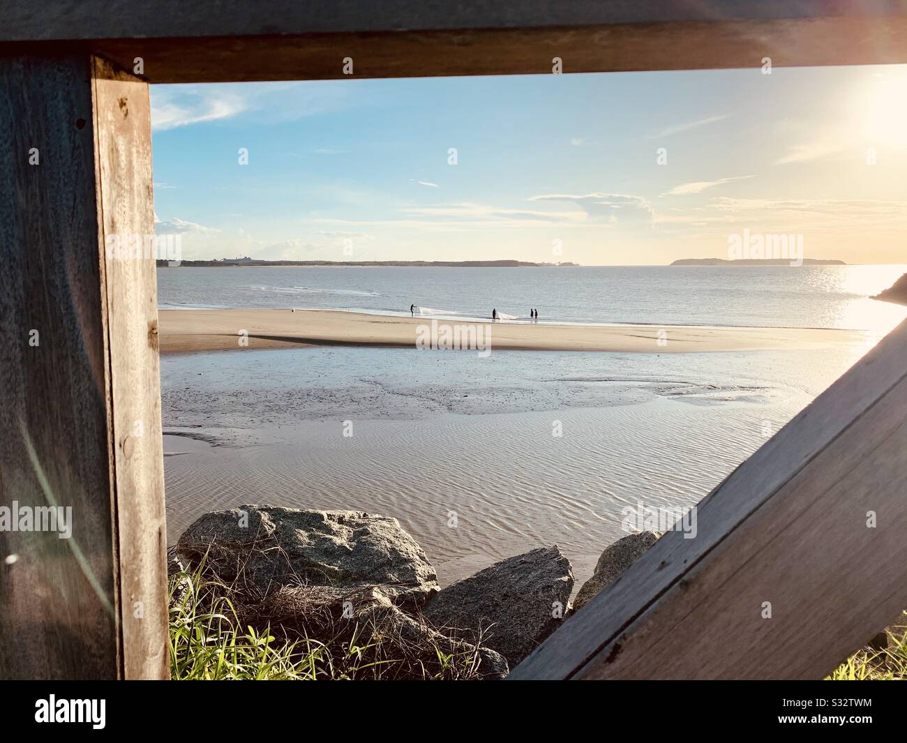 Wooden parapet framing beautiful sunset on the Beach and fishermen Stock Photo