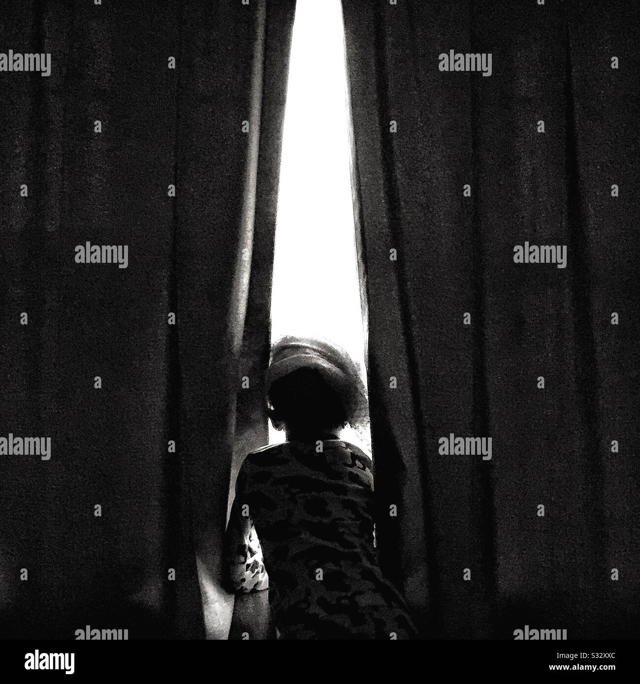 A child sits at a window. - Smartphone Captured Stock Image