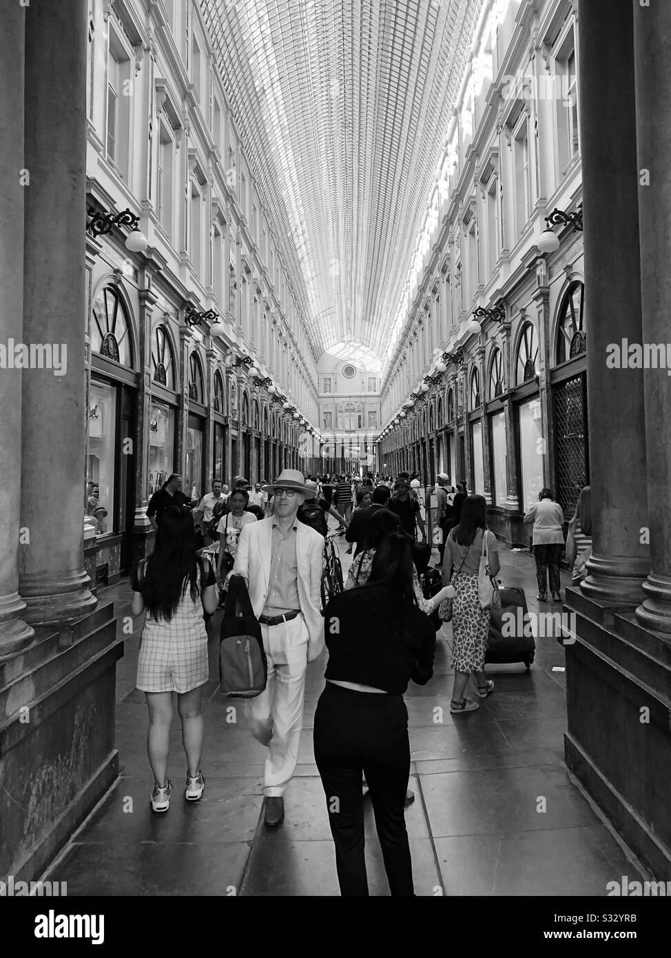 Shoppers going in to and out of Les Galeries Royales Saint-Hubert shopping centre in central Brussels on a busy June weekend. - Smartphone Captured Stock Image