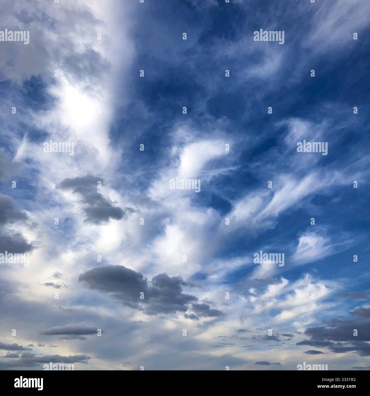 Cirrus and stratocumulus clouds against a blue sky. Stock Photo