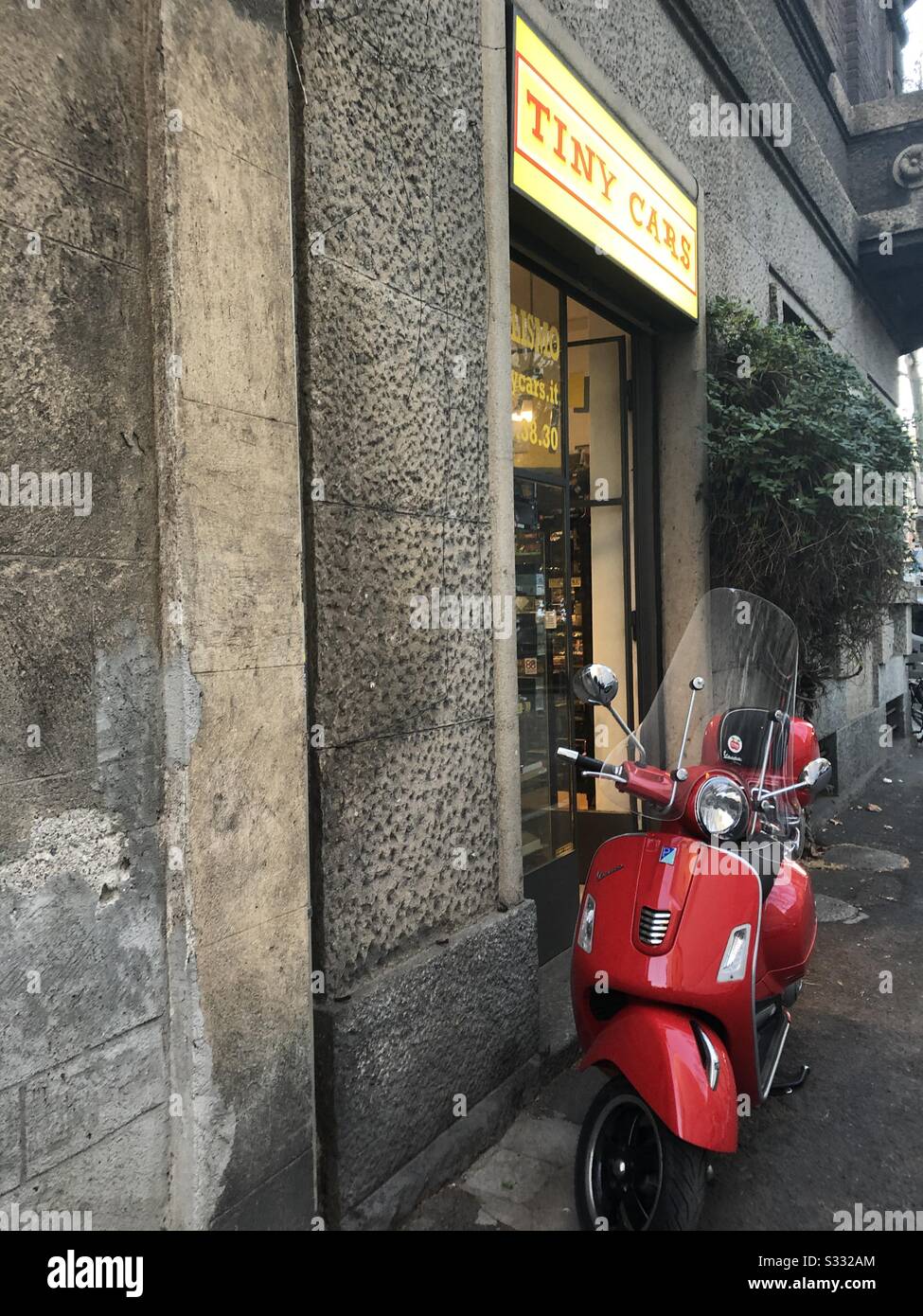 Red Vespa motorcycle outside small shop Milano Italy - Smartphone Captured Stock Image