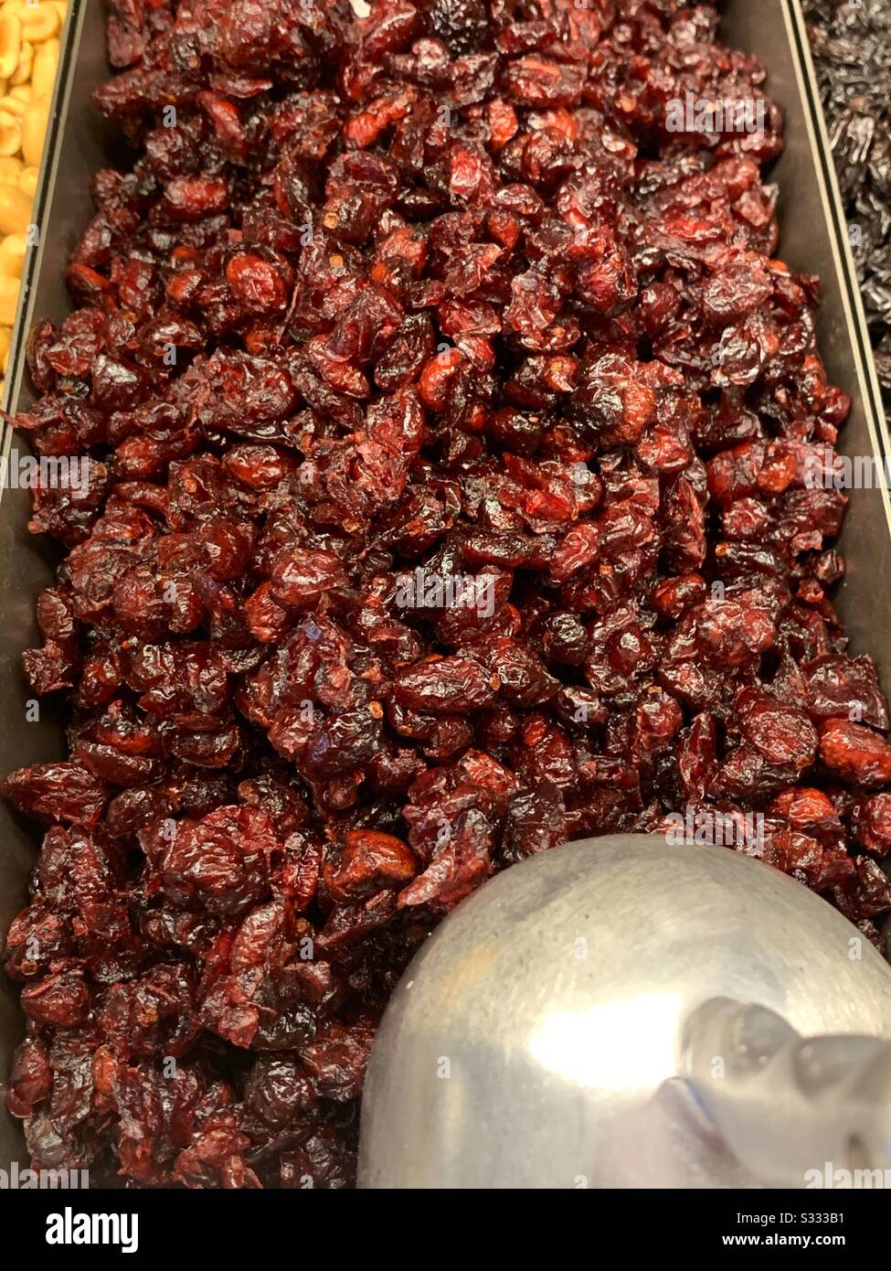 Buffet dish full of dried cranberries with a metal scoop in a trail mix bar Stock Photo